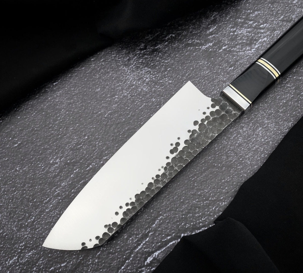 Black Micarta knife handle with thin light and gold-colored spacers and polished collar