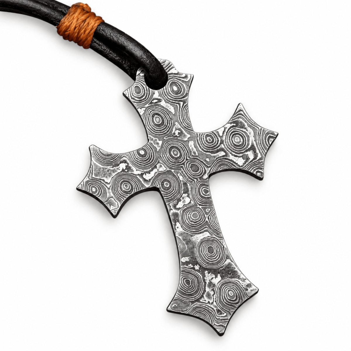 Close view of layered Damascus steel pattern on a cross necklace