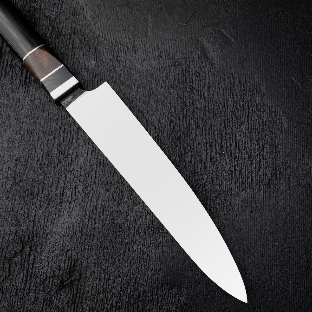 Long stainless steel kitchen slicing knife shown from above on dark background