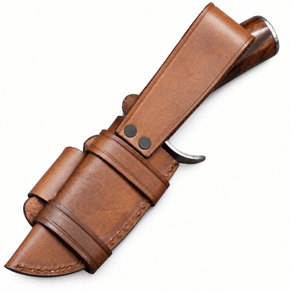 Small Damascus Bowie knife resting beside its leather sheath