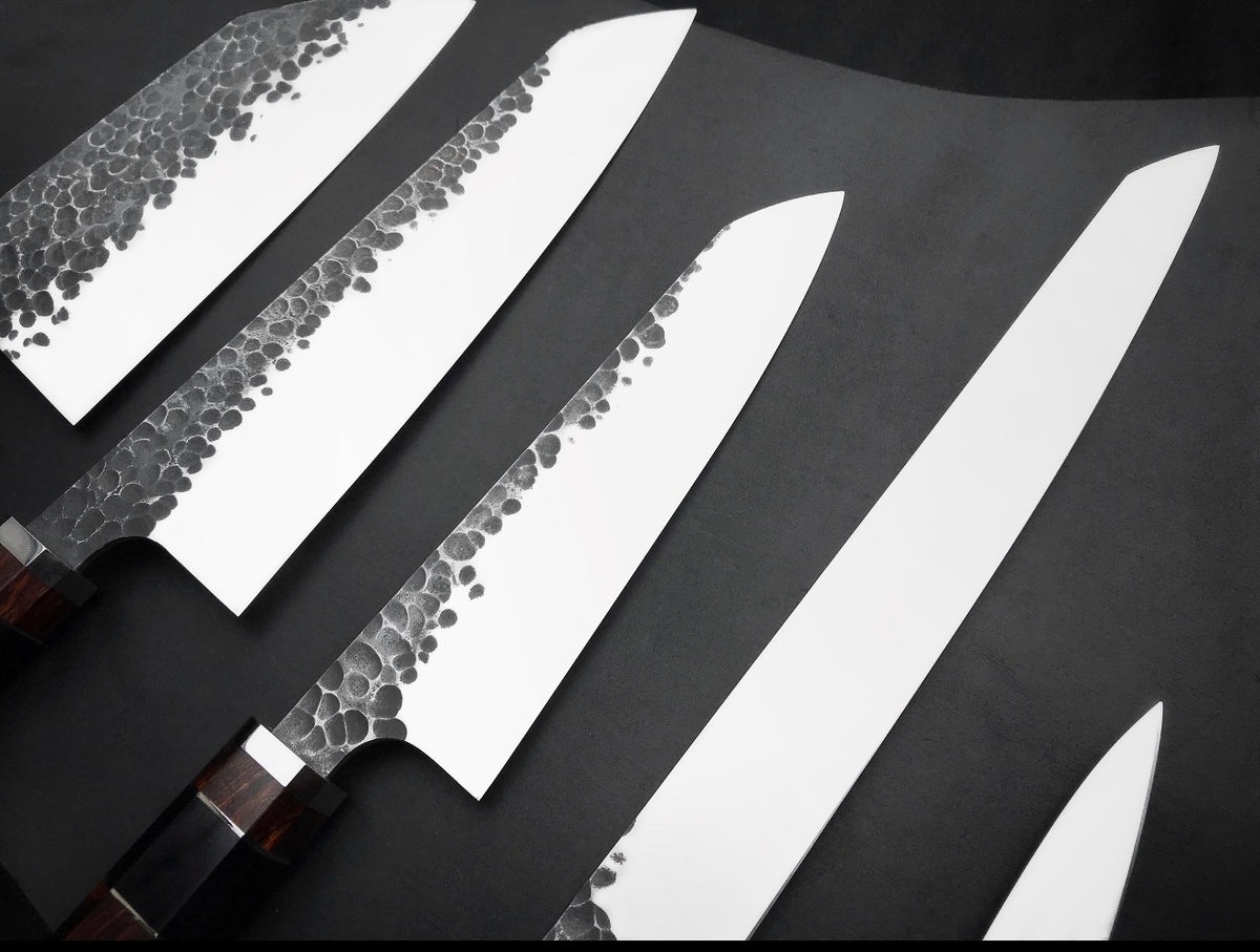 Five 440C kitchen knives from small paring size to long slicer laid out in a row
