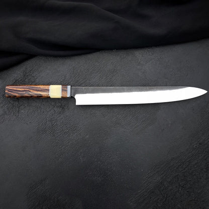 Handmade 10 inch kitchen slicing knife with pointed tip and dark finish near the heel
