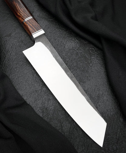 Handmade 8 inch kitchen knife with flat edge and dark textured finish near the heel
