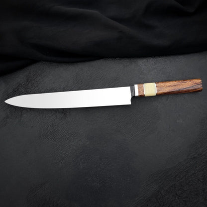 Long stainless steel carving knife lying diagonally on dark leather-look background