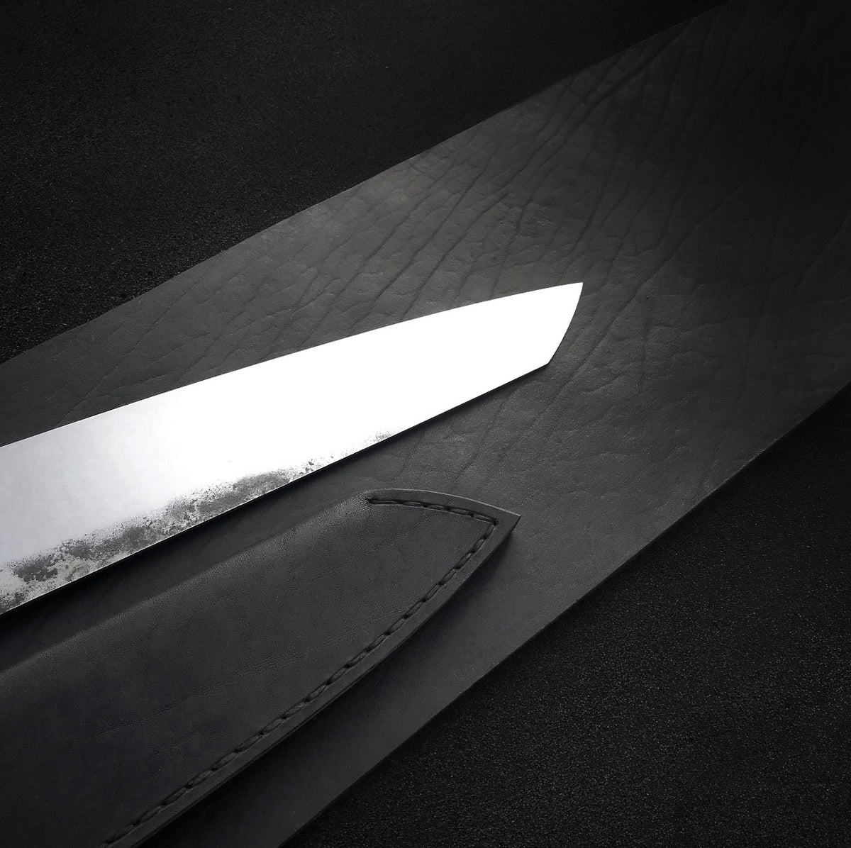Black leather knife sheath with stitched edge and retaining strap with snap
