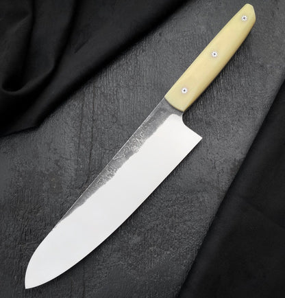 Santoku blade chef knife with polished 440C blade and cream camel bone handle on dark surface
