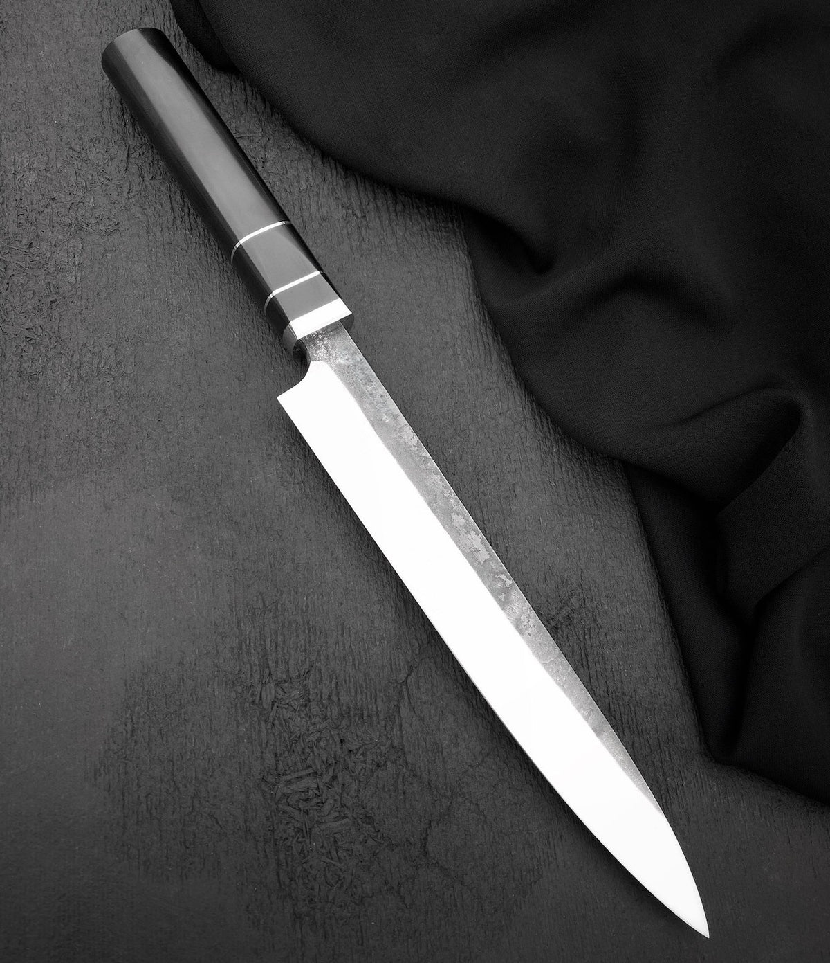 Long slicing knife with polished 440C blade and black octagonal Micarta handle on dark surface
